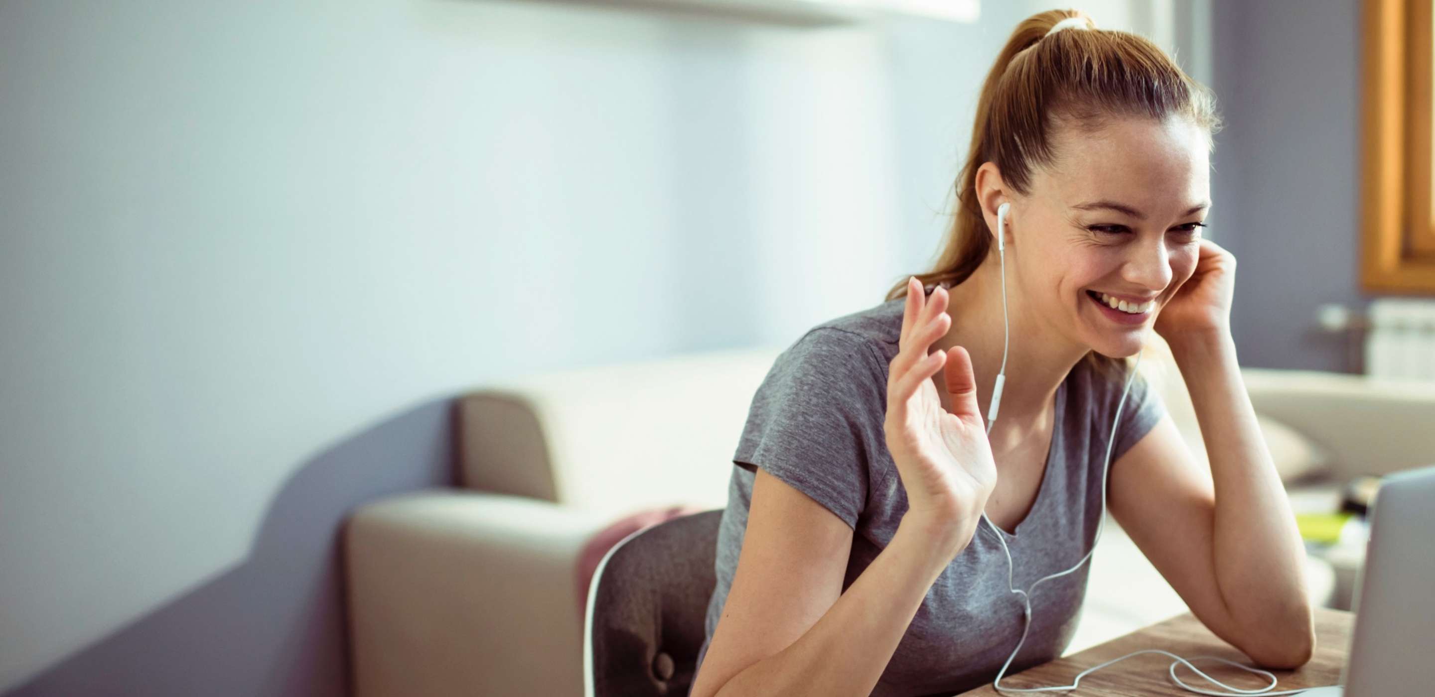 smiling woman talking on mobile phone sitting at desk with laptop open in front of her