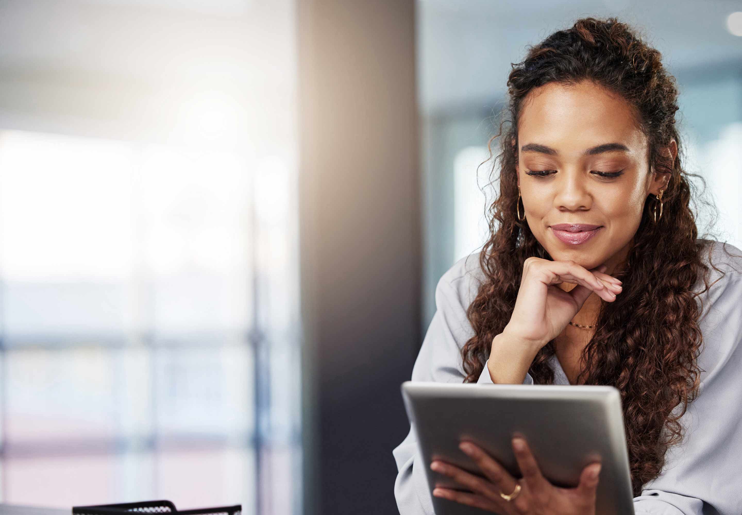 Smiling young woman looking down at tablet device in hand