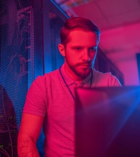 A man in a room with a red light looking at a monitor