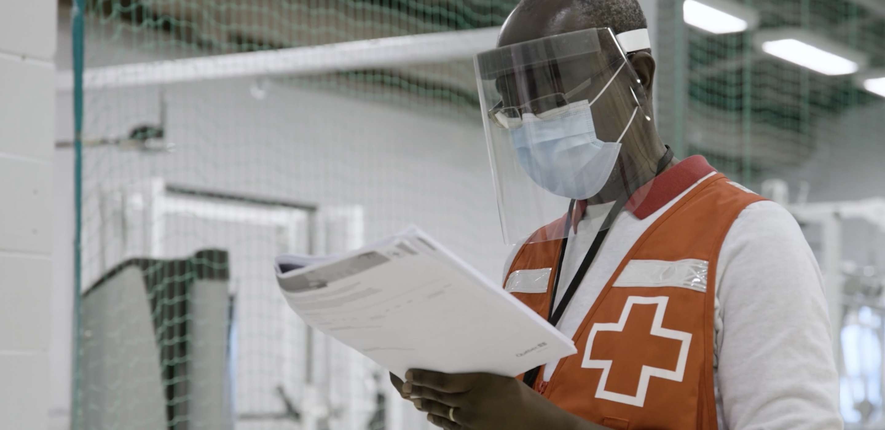 Canadian red cross member wearing face screen and mask viewing folder in hands 