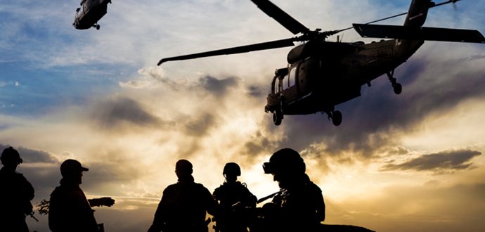 Silhouettes of people with a helicopter in the sky