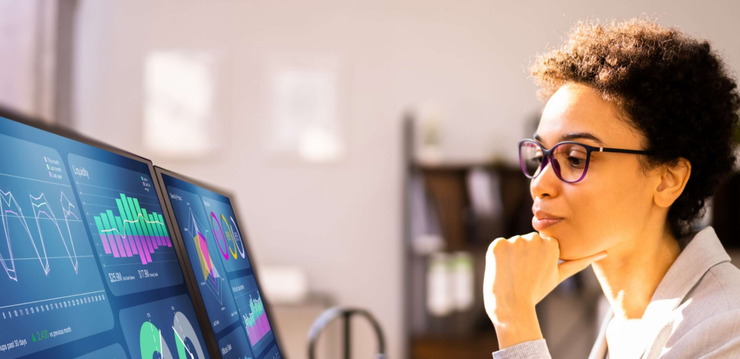 A woman wearing optical glasses looking at two screens with data