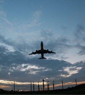 Silhouette of an airplane flying in front of cloudy sky