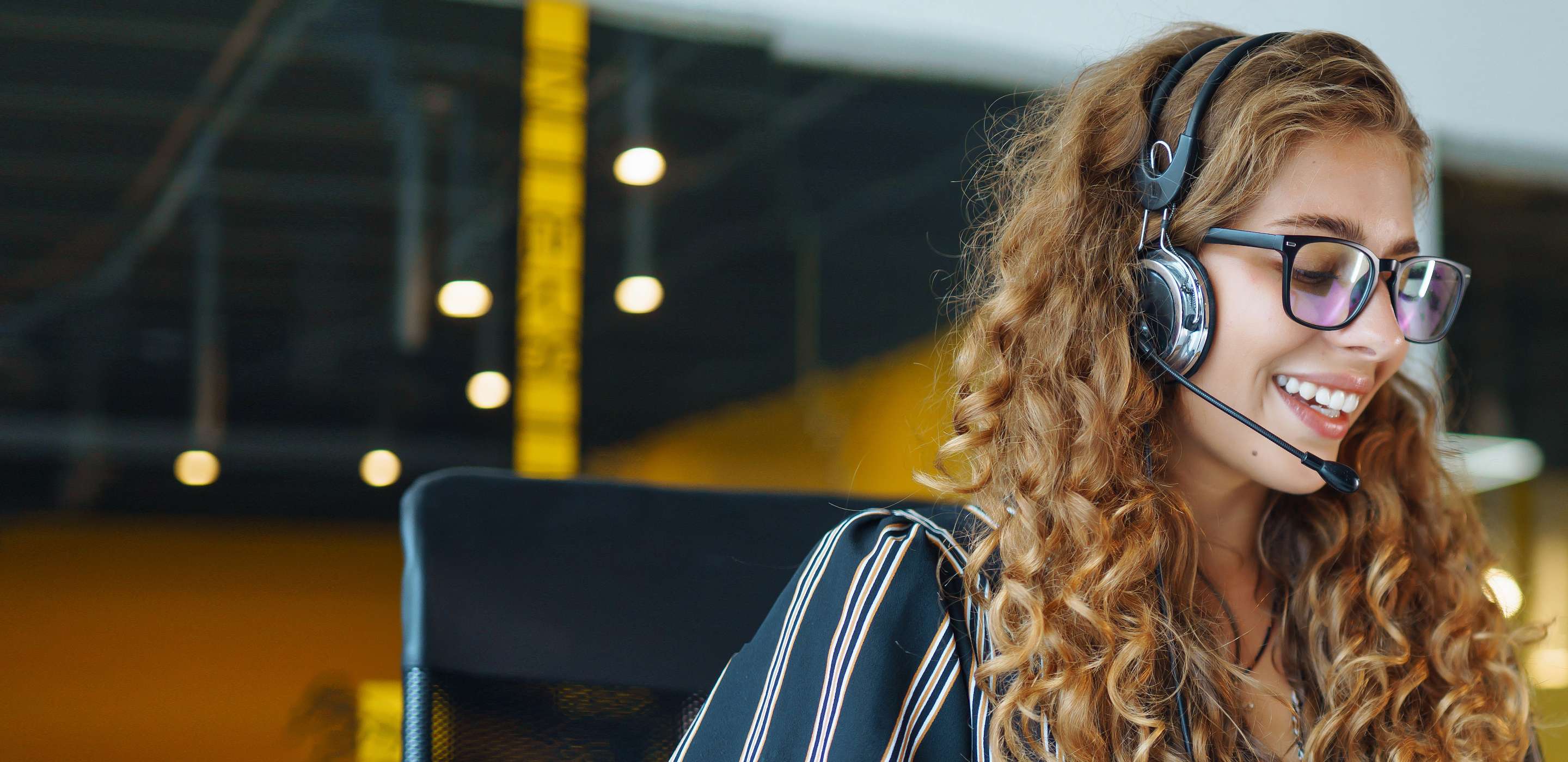 Smiling young woman wearing headphones using laptop