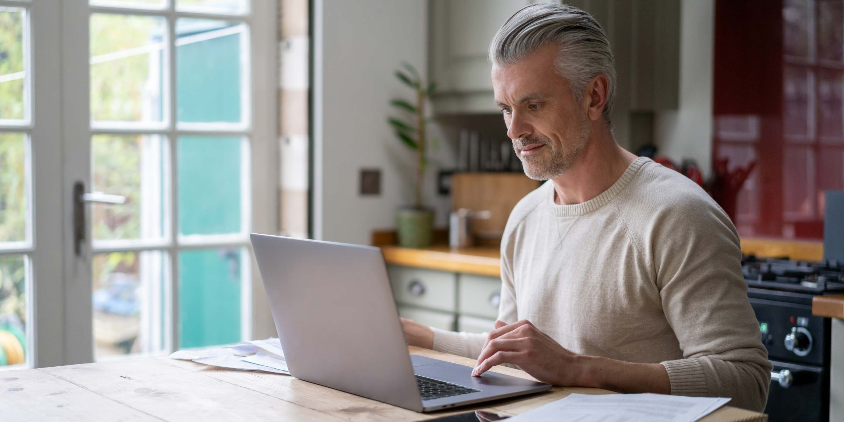A man sitting down looking at a laptop on top of a desk