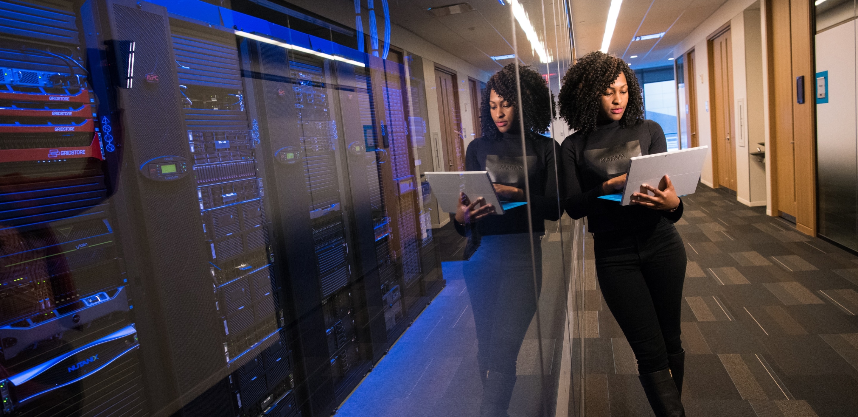 Lady with open laptop standing outside the server room