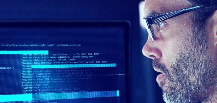 A man wearing glasses looking at a screen with data