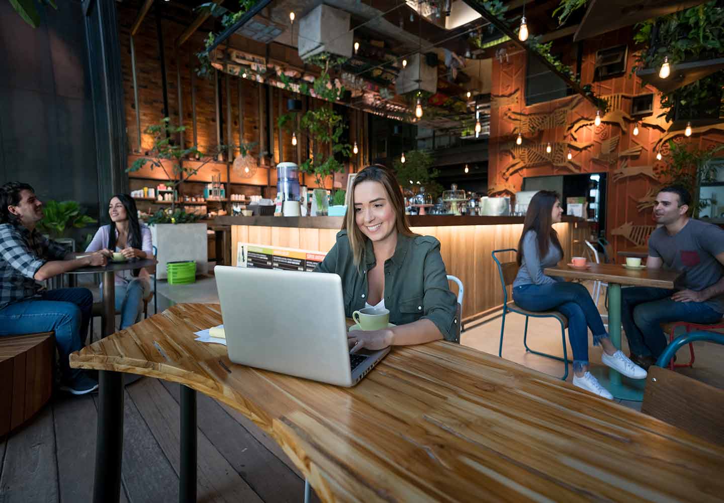 A lady sitting in a coffee shop looking at a laptop screen
