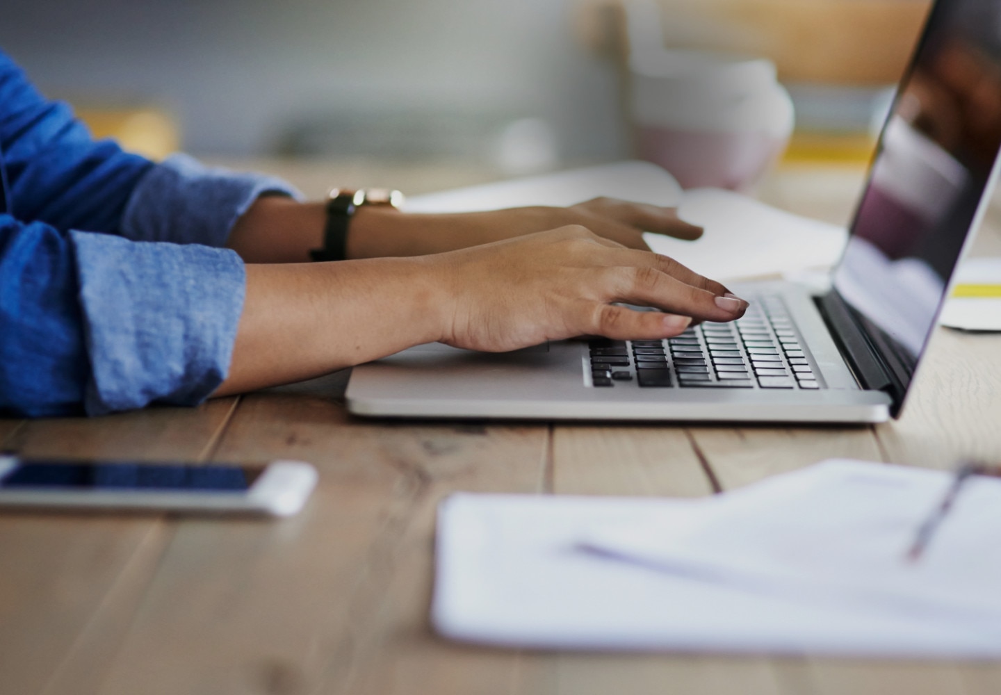 Hands type on laptop keyboard