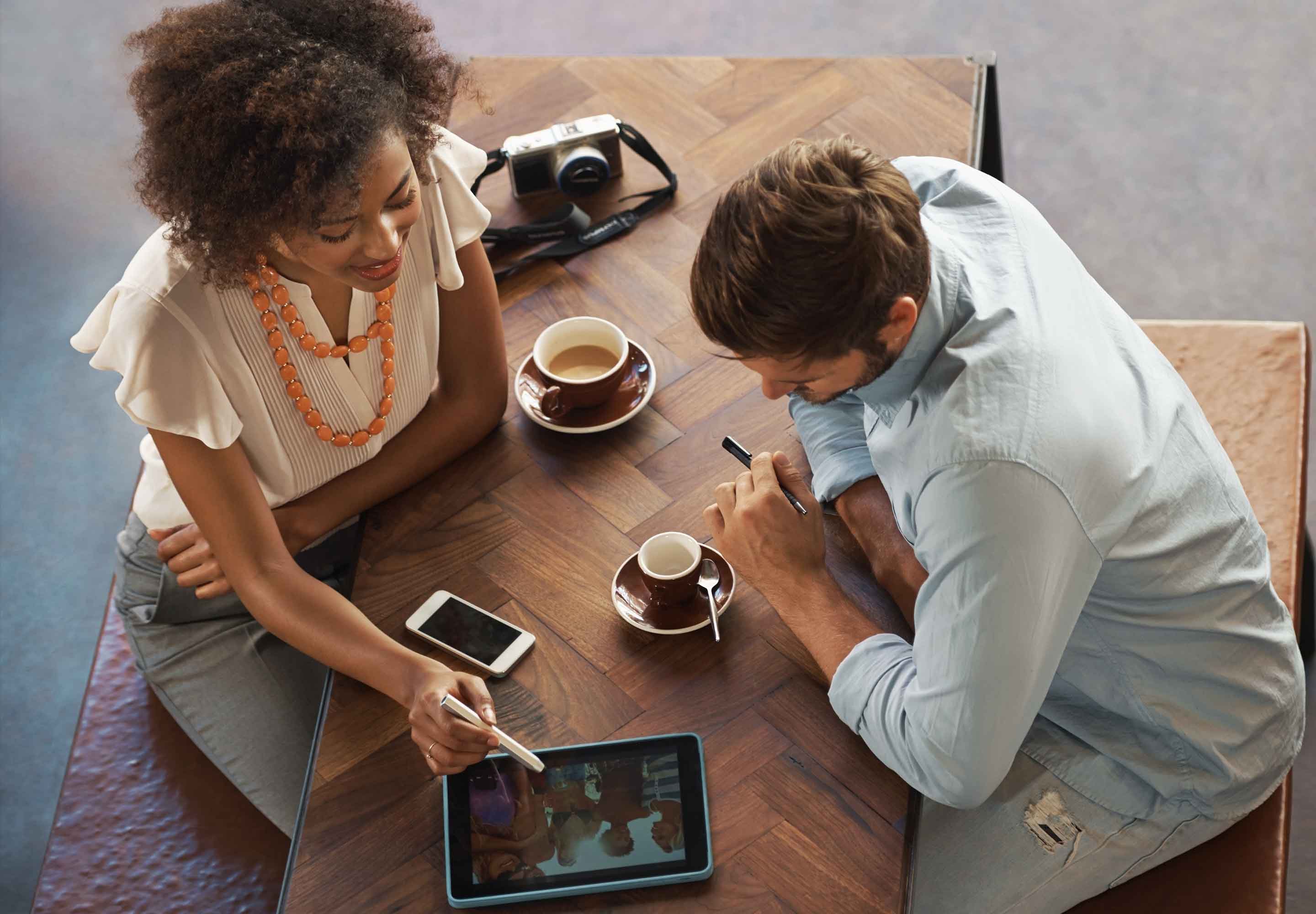 A woman showing a man info on a tablet screen