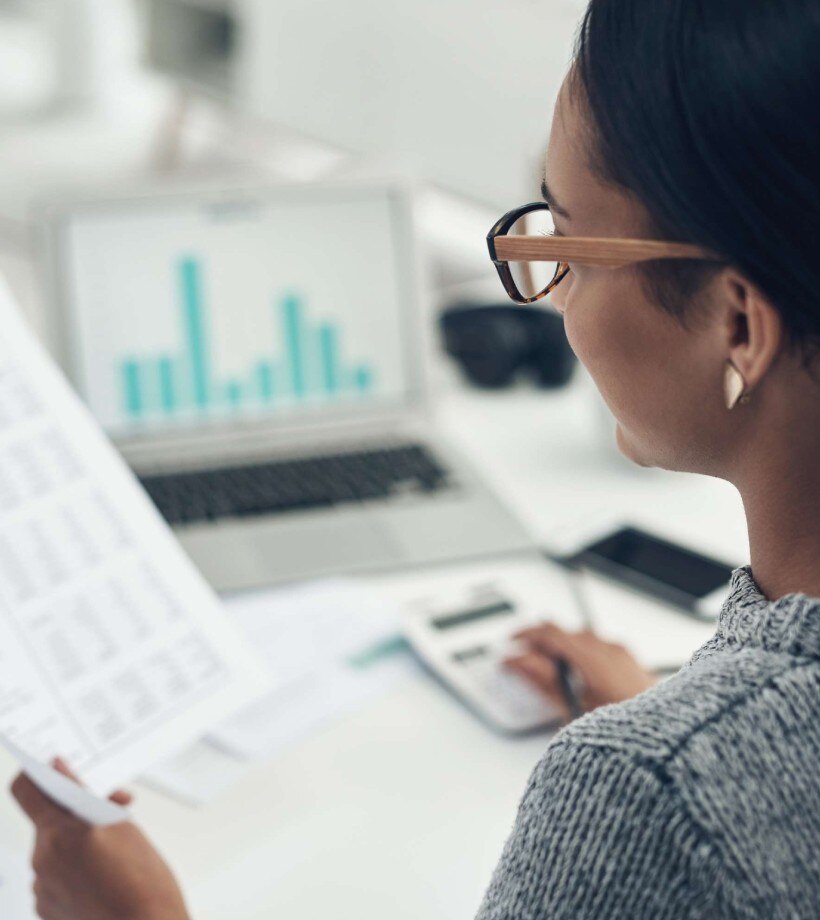 Woman working with calculator, spread sheets and graphs