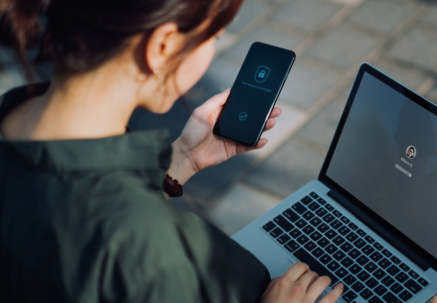 Lady looking at phone and computer with security lock
