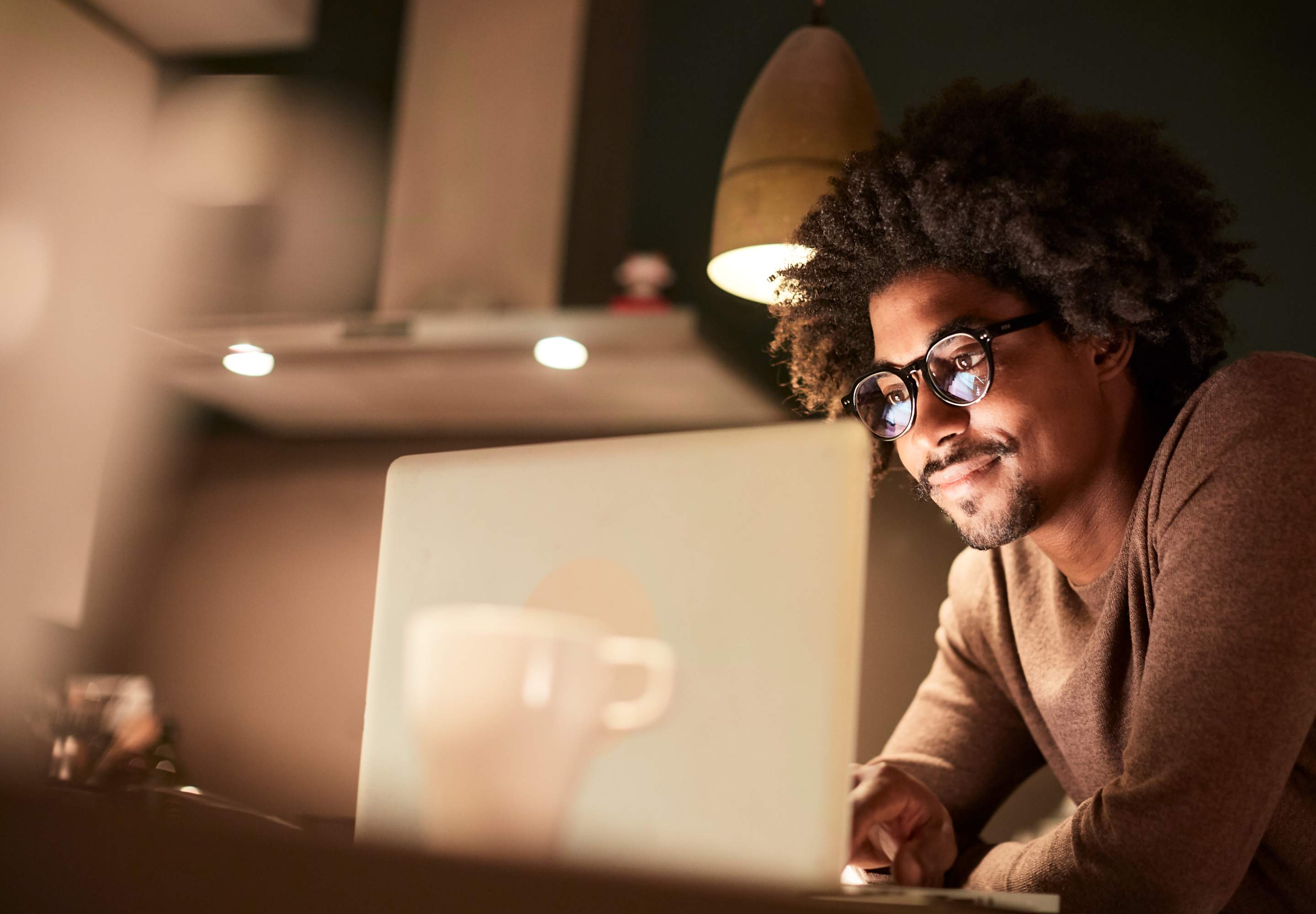 Man in a brown shirt working on his laptop