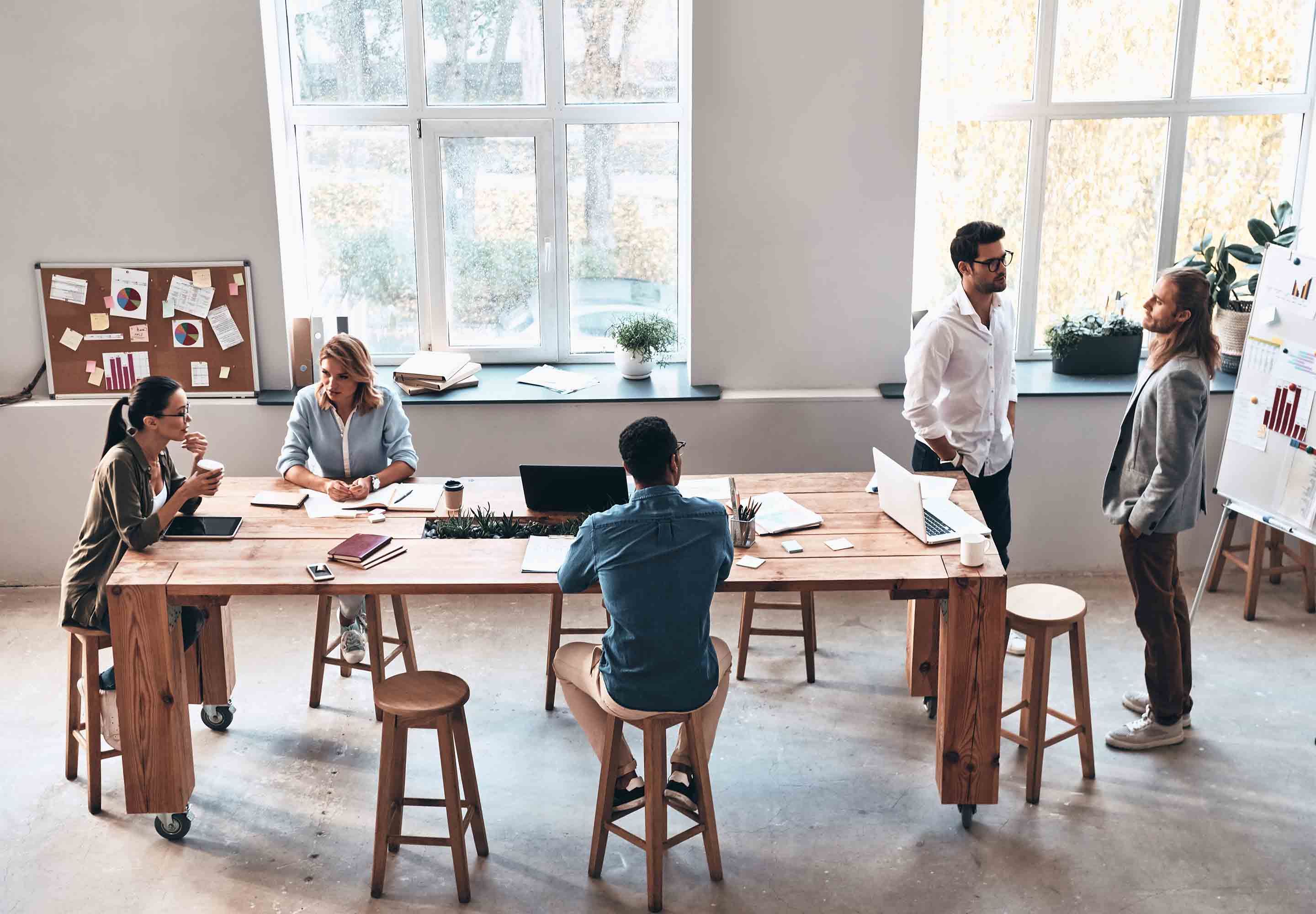 People sitting in long chairs around the table and others standing