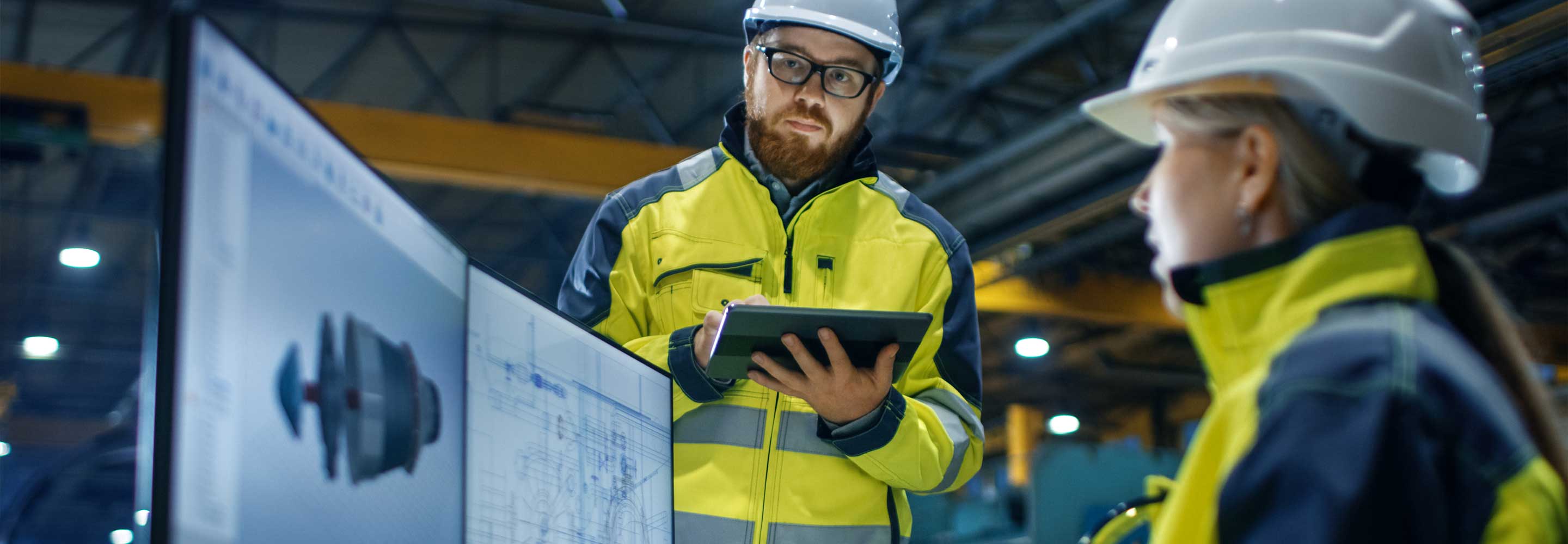 Engineer looking at data on a tablet and computer screen
