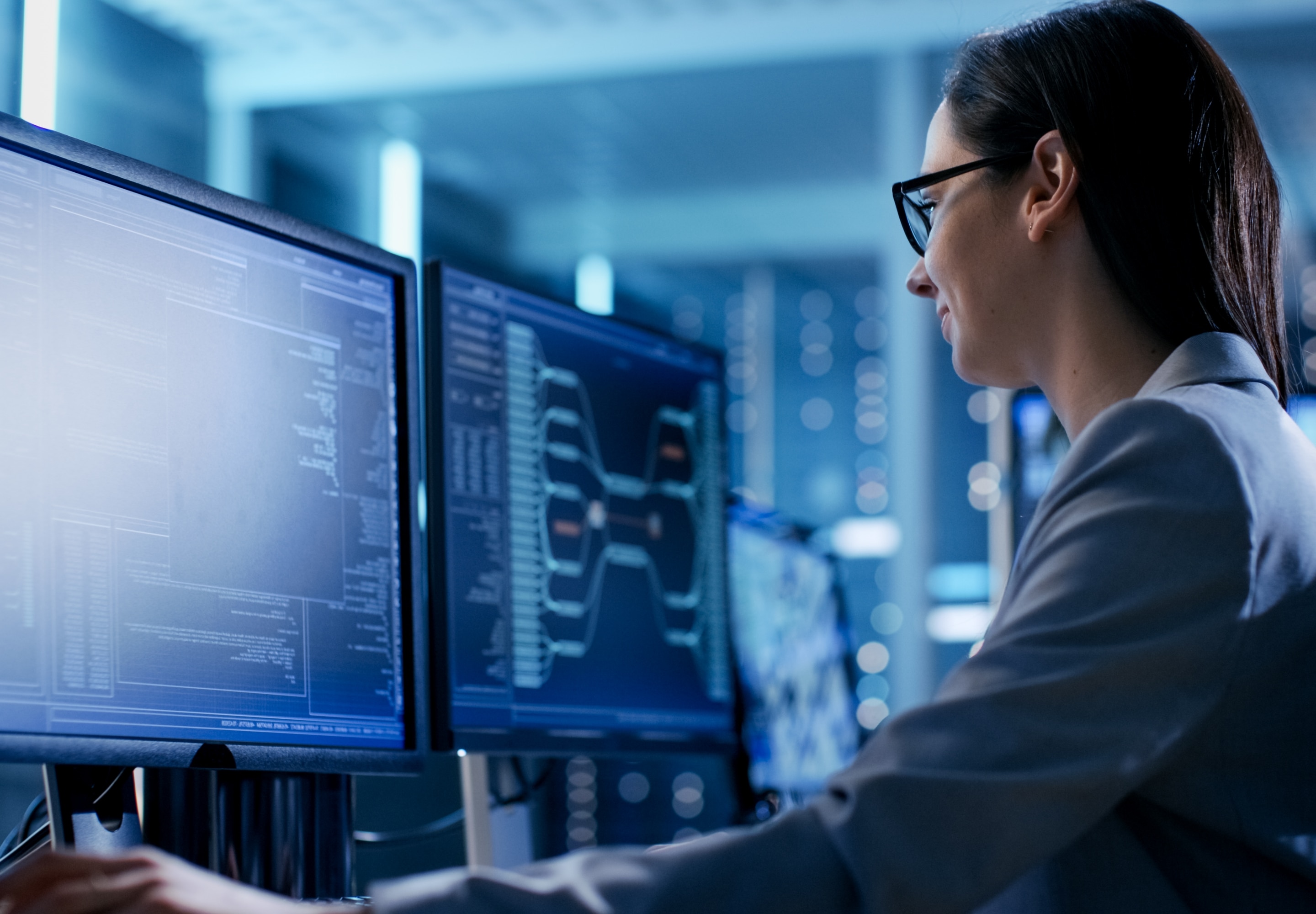 A woman looking at two monitor screens