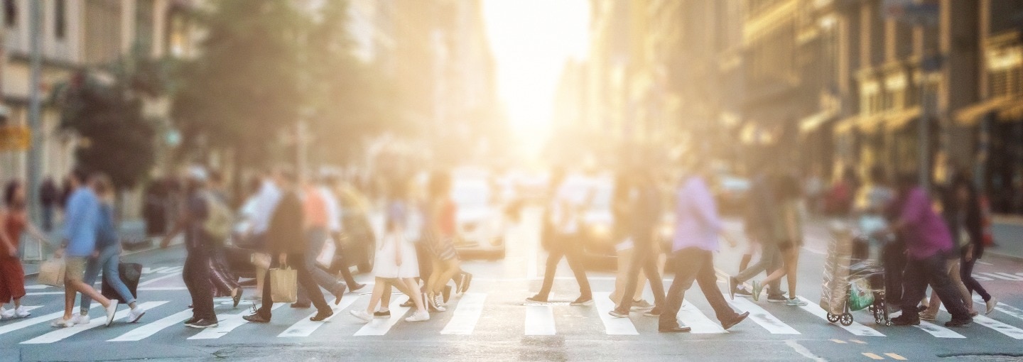 A busy street of people walking across a crossroad