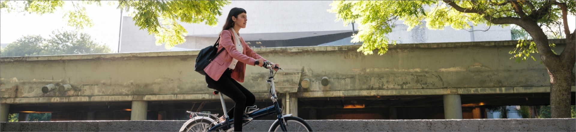 Lady riding bicycle under green trees