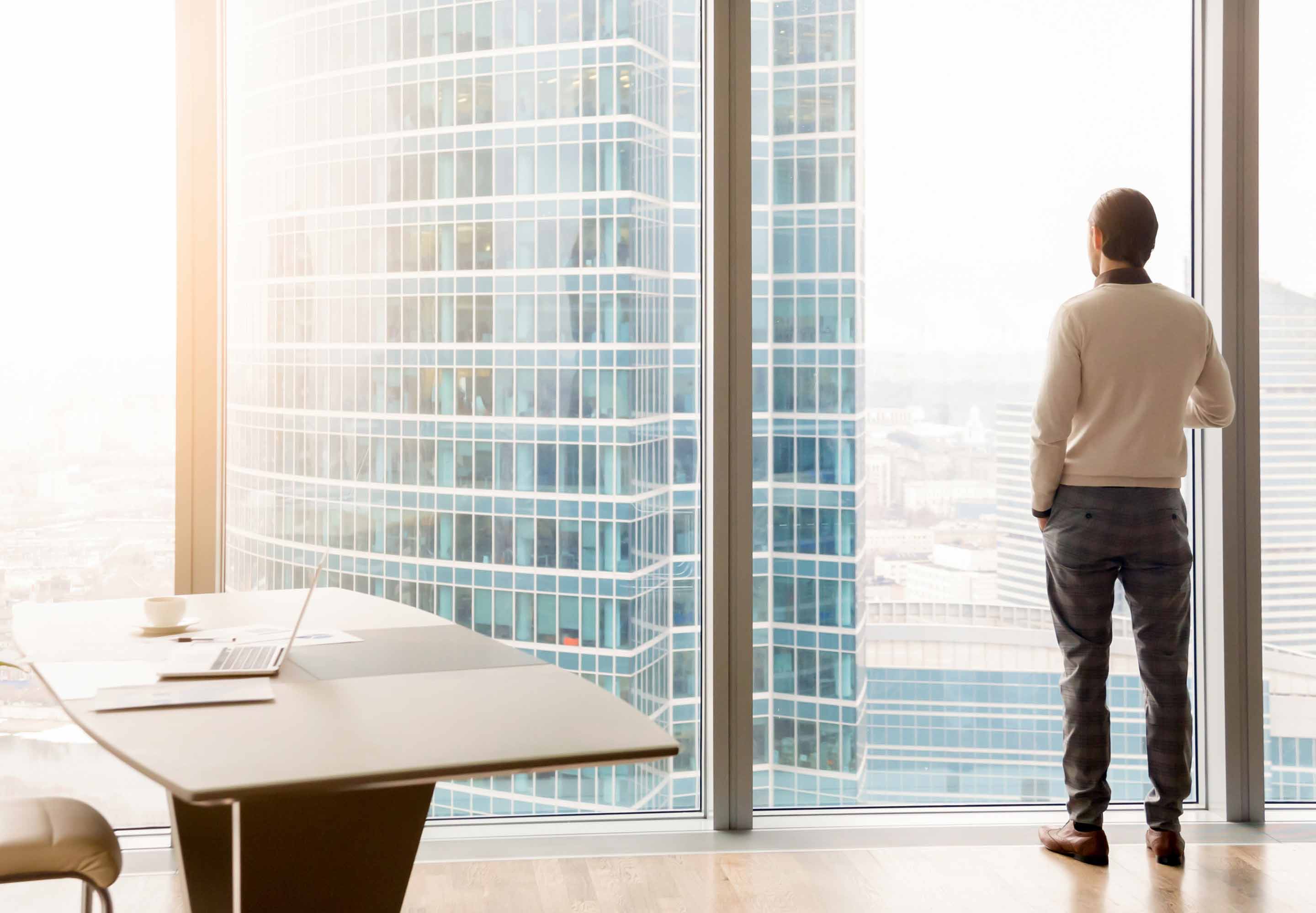 A back view of a man standing in front of a glass building