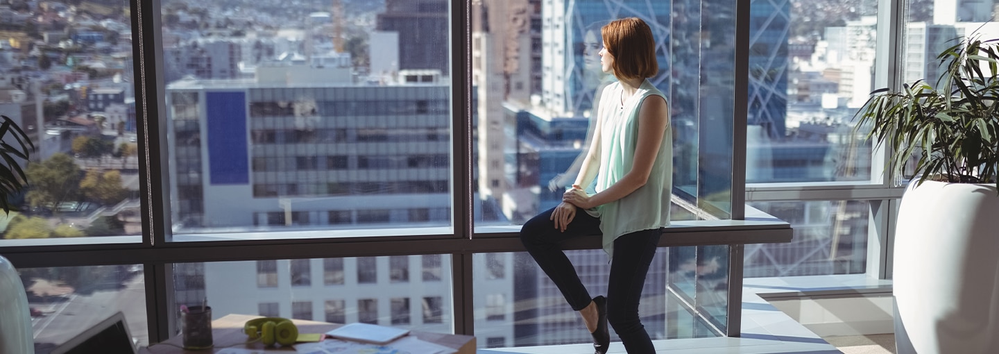 Female looking out of office window at city below