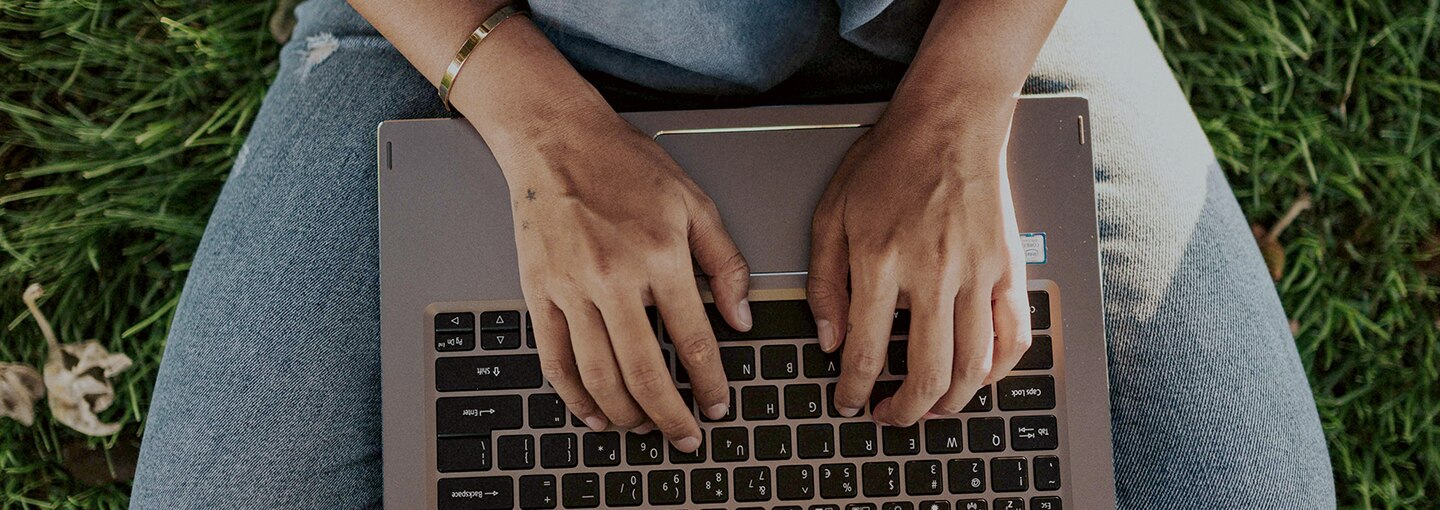 Aerial view of hands on a laptop keyboard on a lap