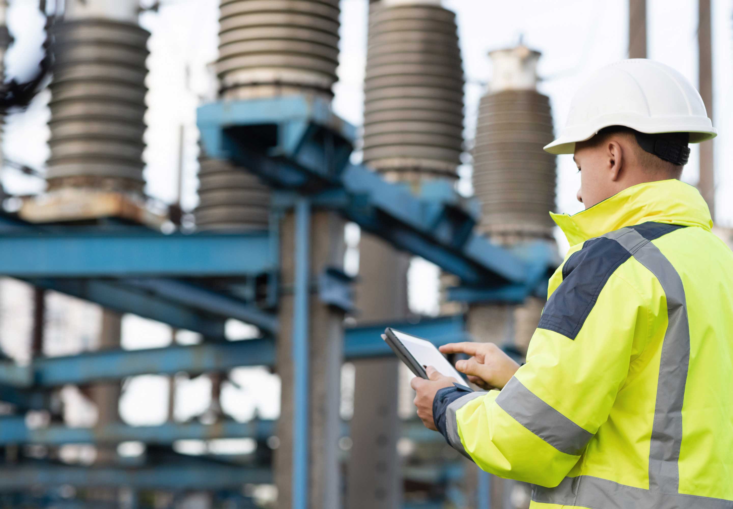 A man in protective wear around steel holding a tablet