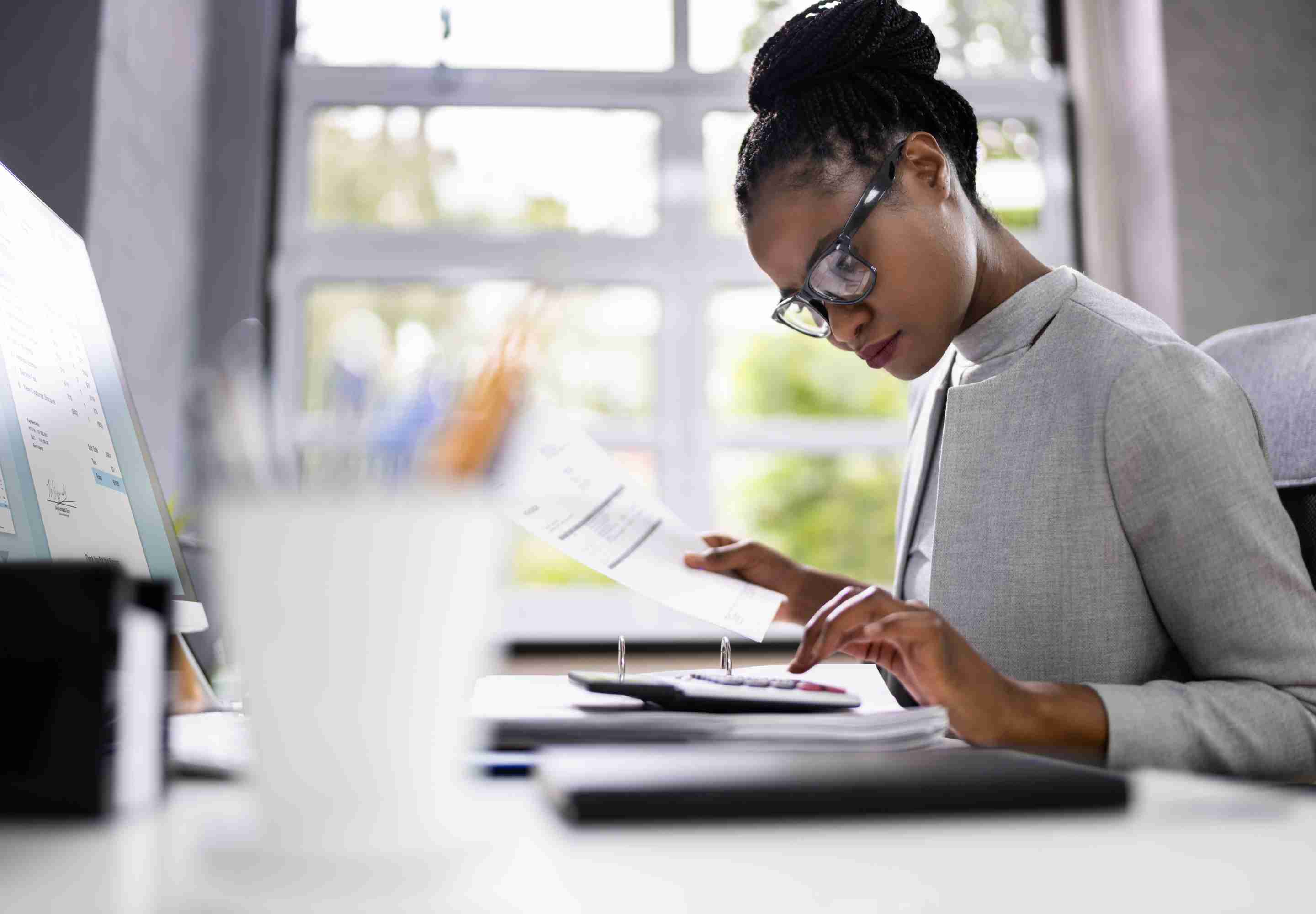 Woman holding a document while typing on her laptop