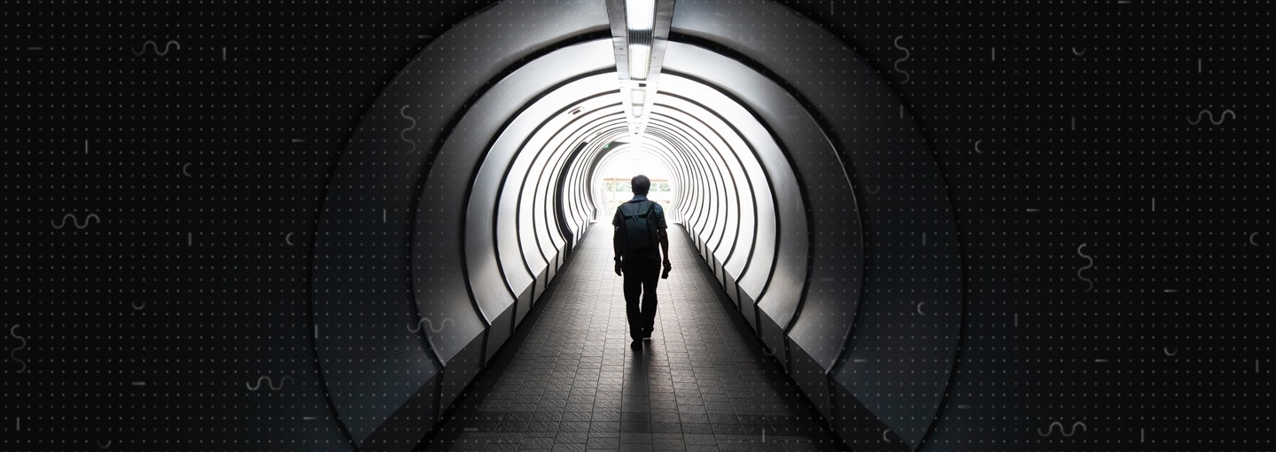A person walking down a tunnel towards the exit