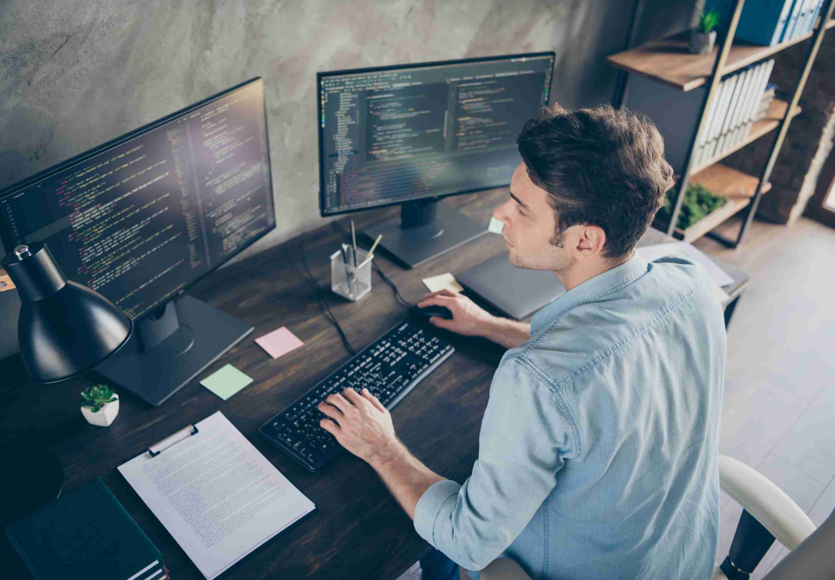 A man looking at 2 computer screens