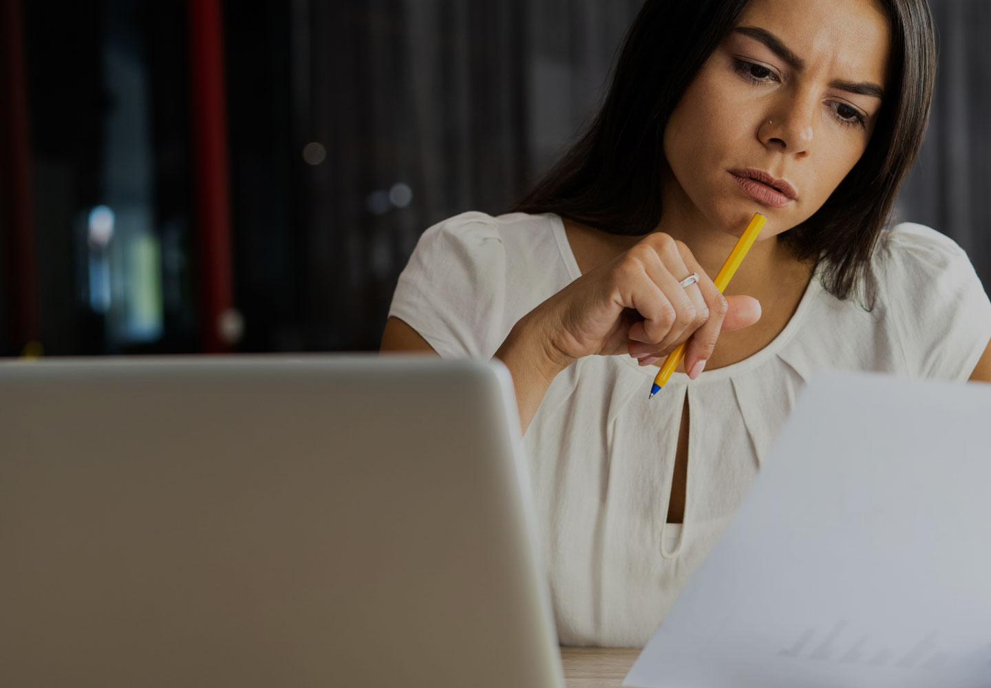 Woman reading paper at desk with yellow pen in hand