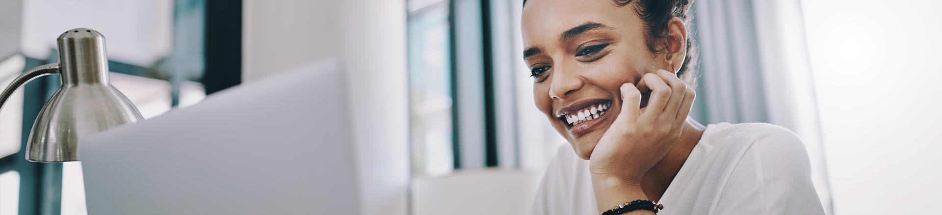 A woman smiling while working on her laptop