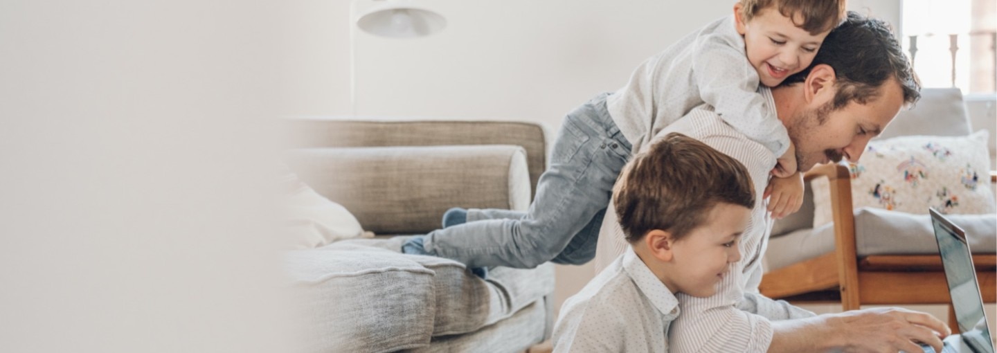 Man working from home with his kids climbing over him