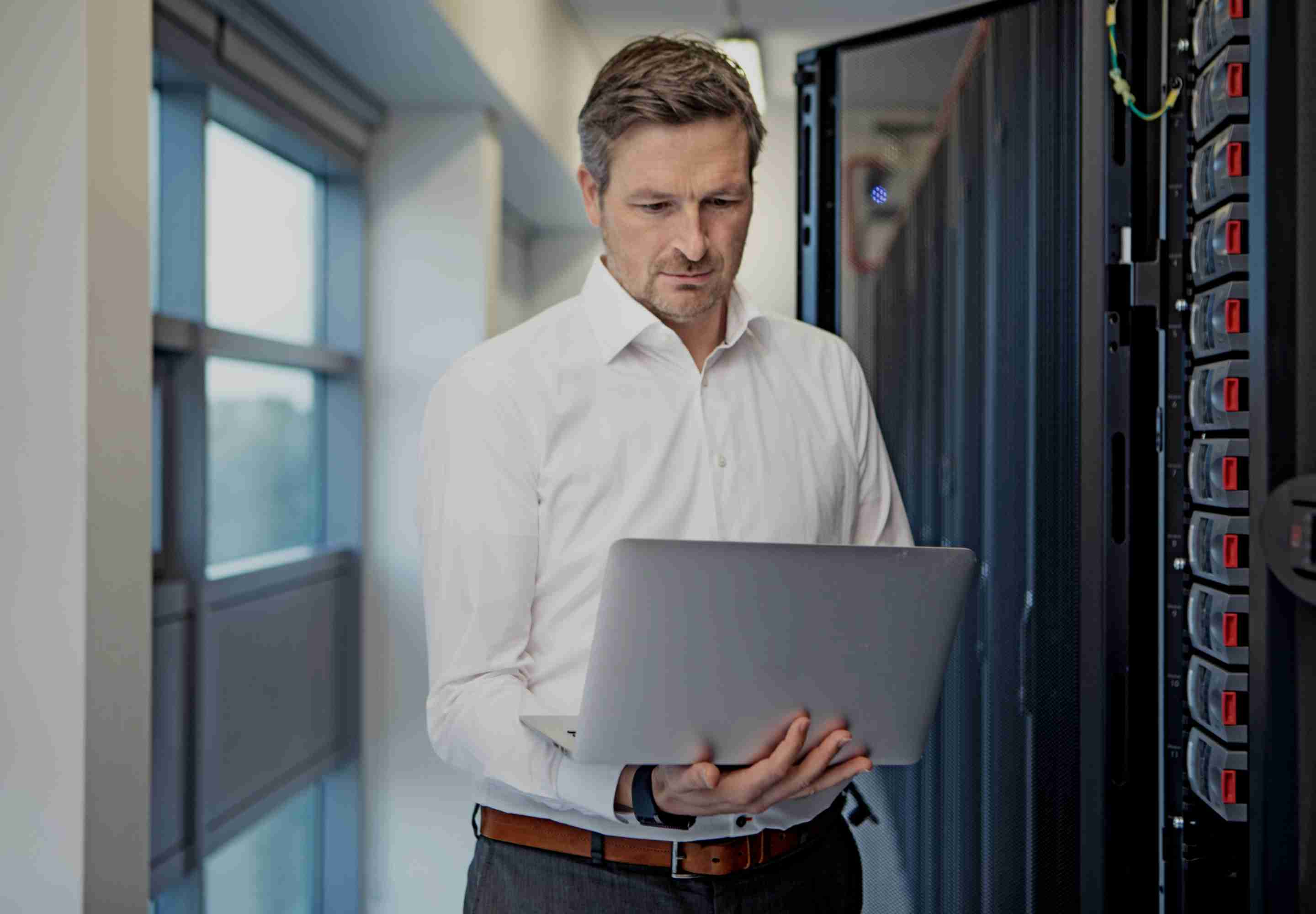 Man in data center studies laptop
