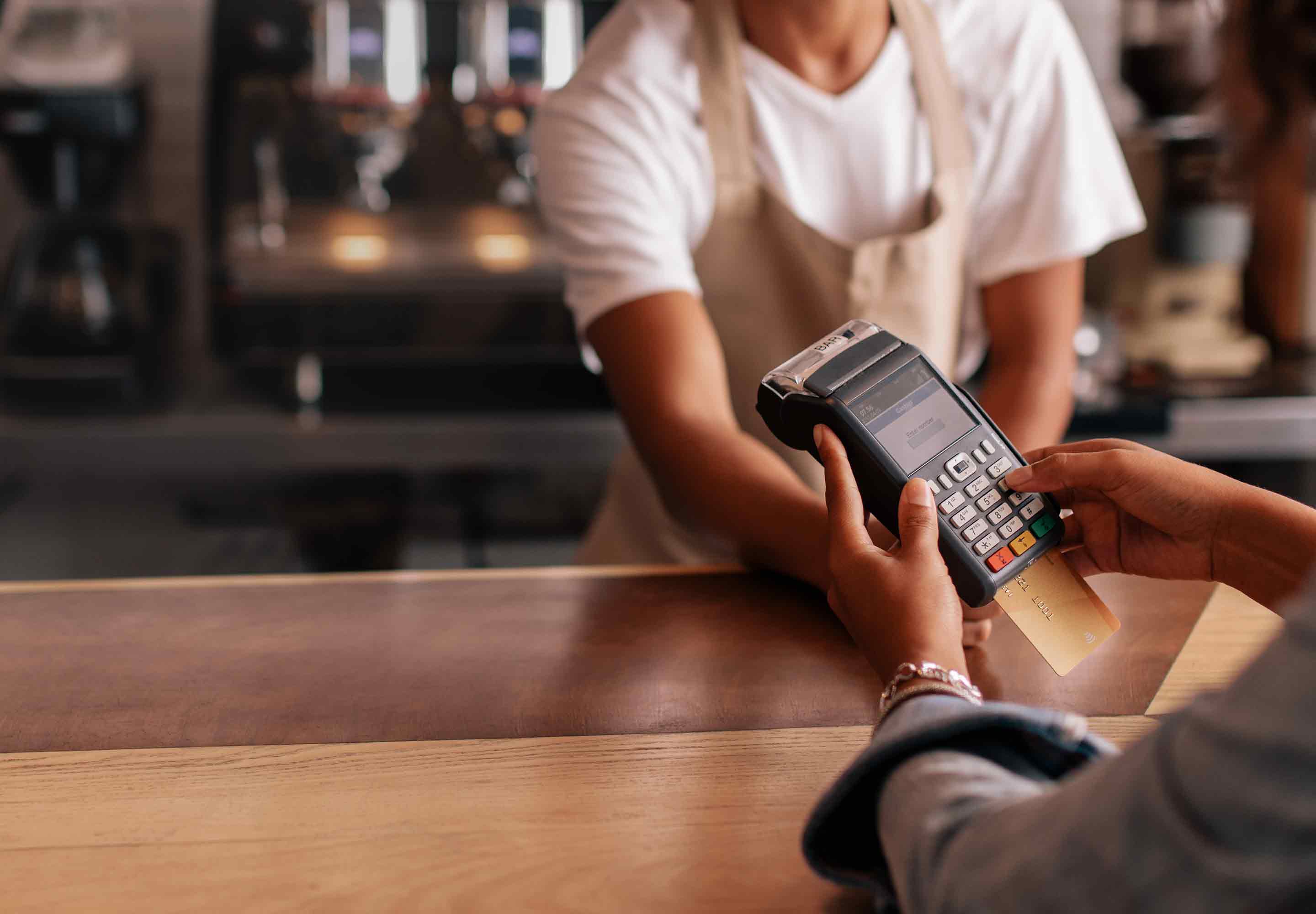 A customer holding card machine across a service desk