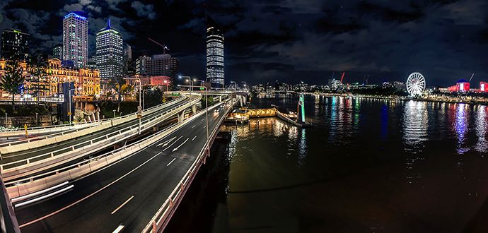Road with light trails at night next to water