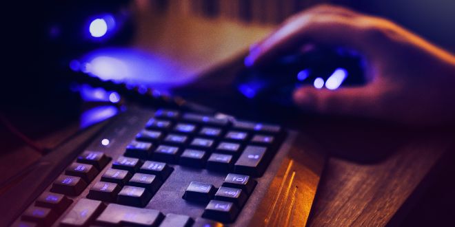 Hand holding a computer mouse next to a keyboard
