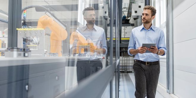 Man holding tablet while walking and looking into a window