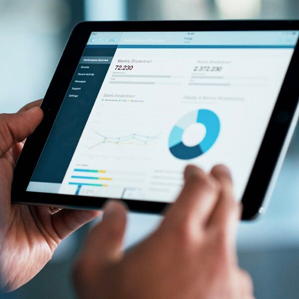 Office worker holding devices showing data charts and diagrams