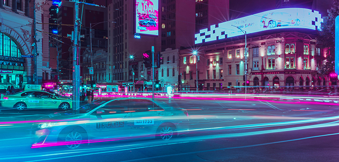 Autos auf einer Straße mit blauen und rosa Lichtspuren bei Nacht 