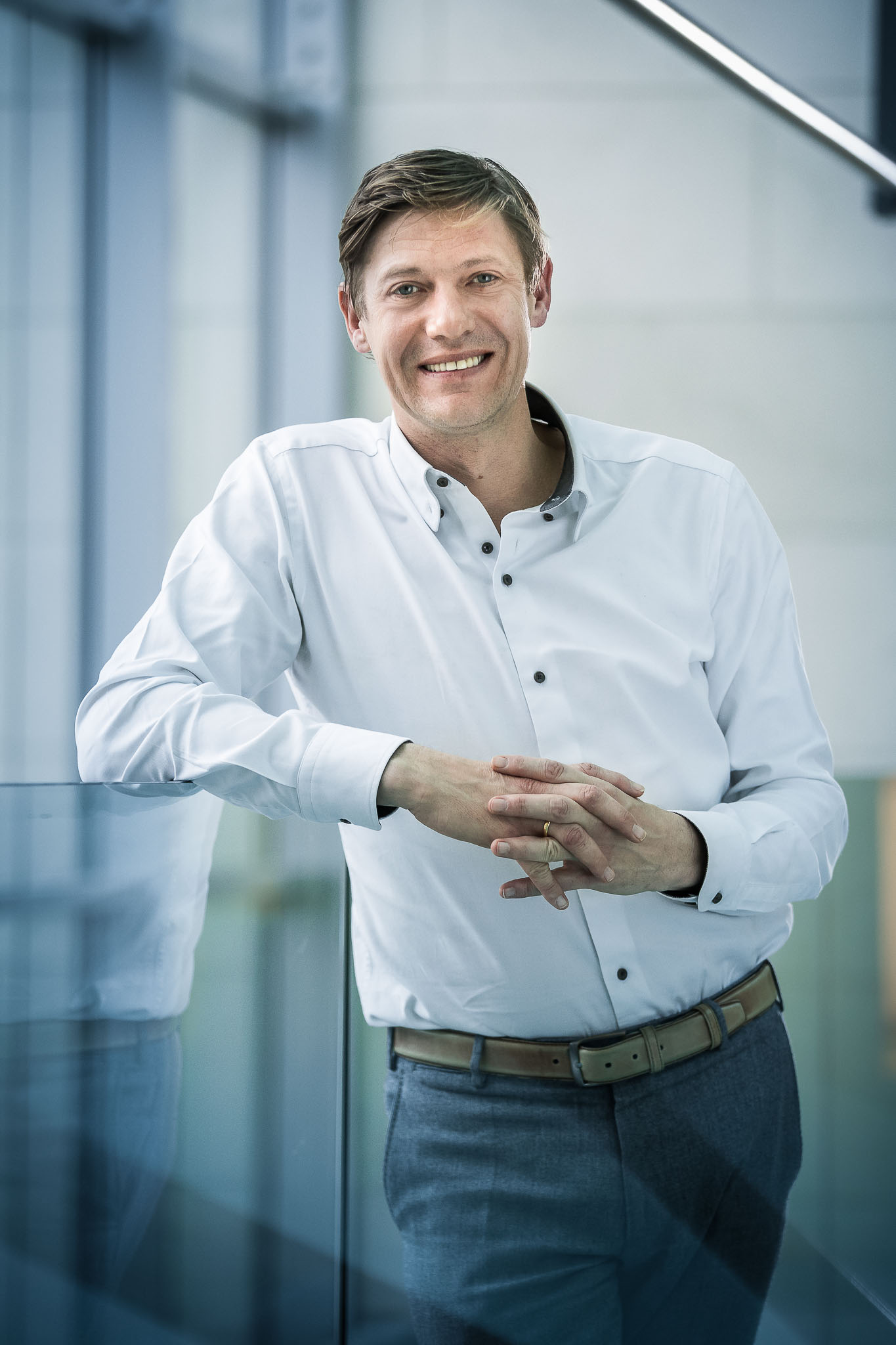 A man wearing a shirt and jeans standing and smiling 