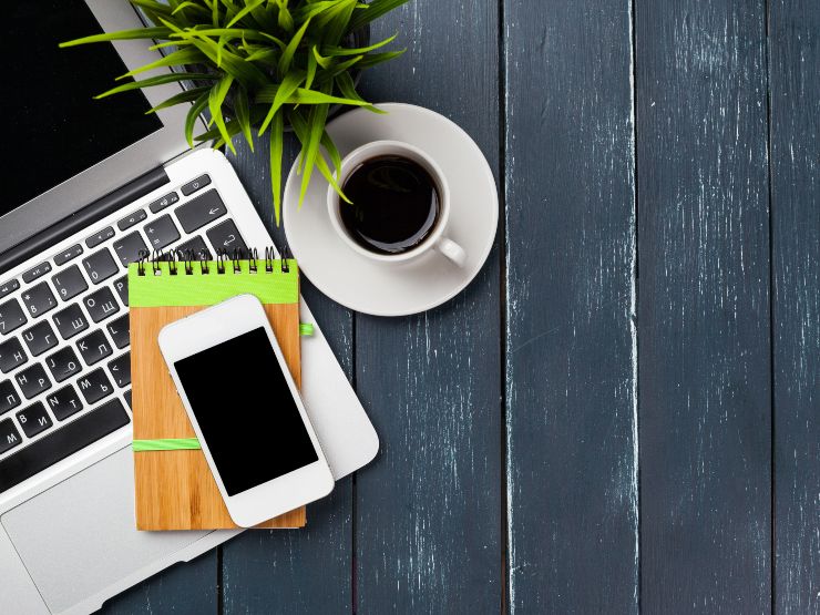 Areal view of a desk with a laptop, phone and coffee