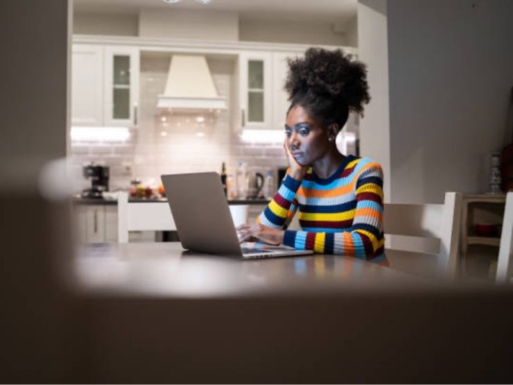 Woman looking at laptop at dining room table