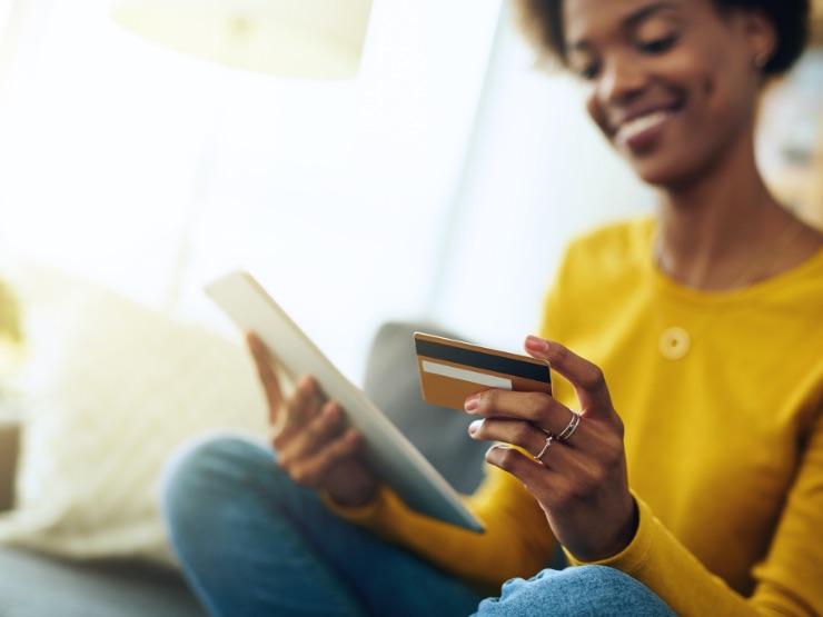 Lady holding a tablet looking at her bank card