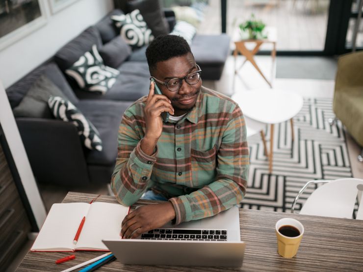 Man talking on his mobile phone in front of a laptop