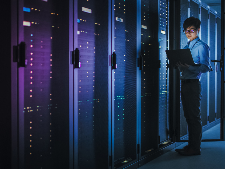 A man standing next to servers with a laptop