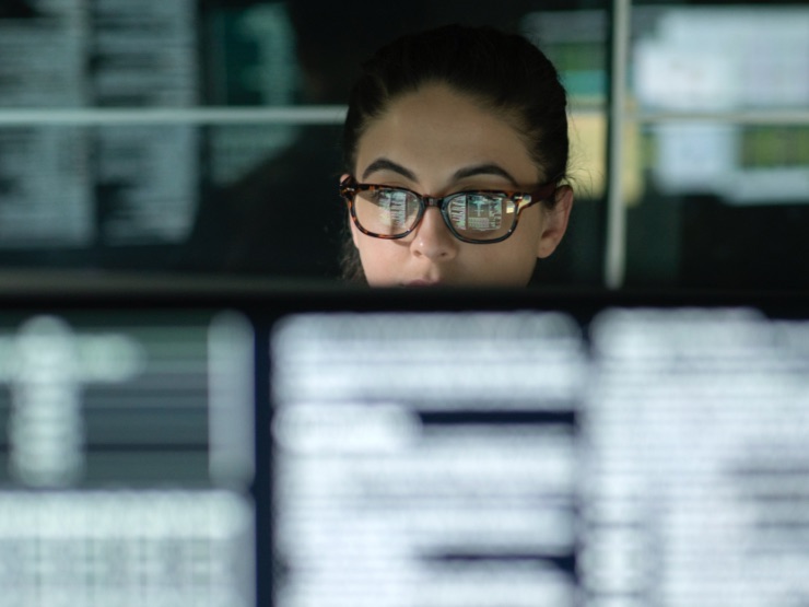 A woman sitting at her desk with screens