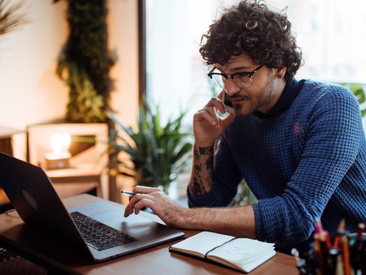 Man talking on phone and using laptop