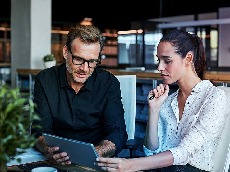 Two people sitting together and looking at a tablet
