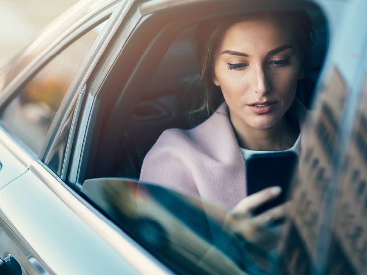 A person in the back of a car on their phone