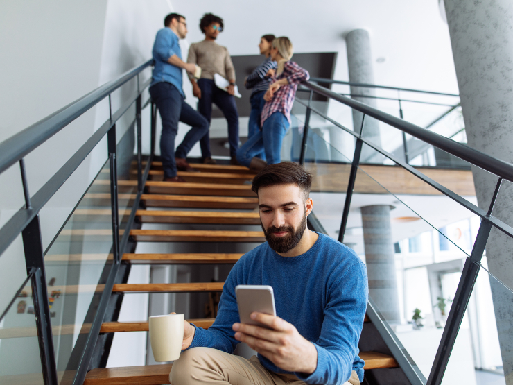 A man sitting on wooden stairs while on his phone